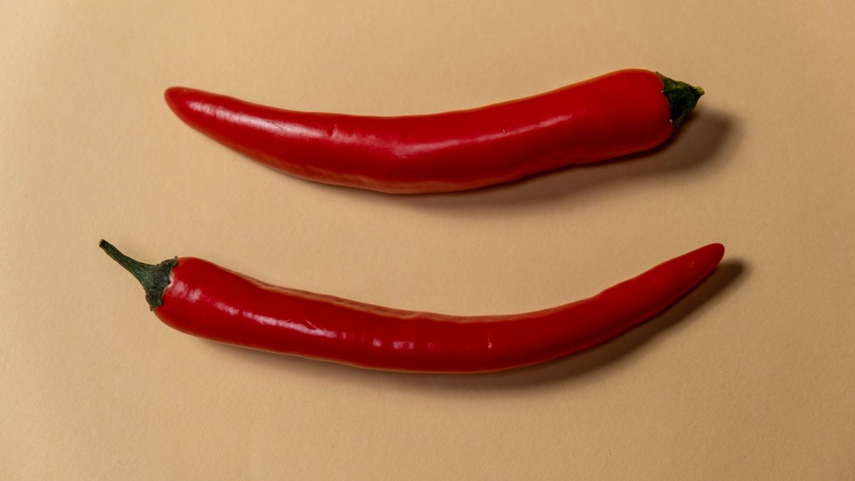 Dva červené chilli lusky na béžovém pozadí