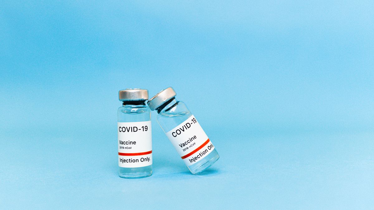 Dvě lahvičky vakcíny proti covidu-19 na modrém pozadí